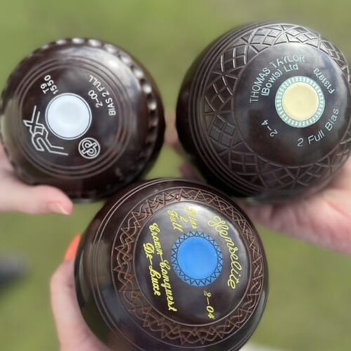 Three crown green bowling balls, each held by a different person.